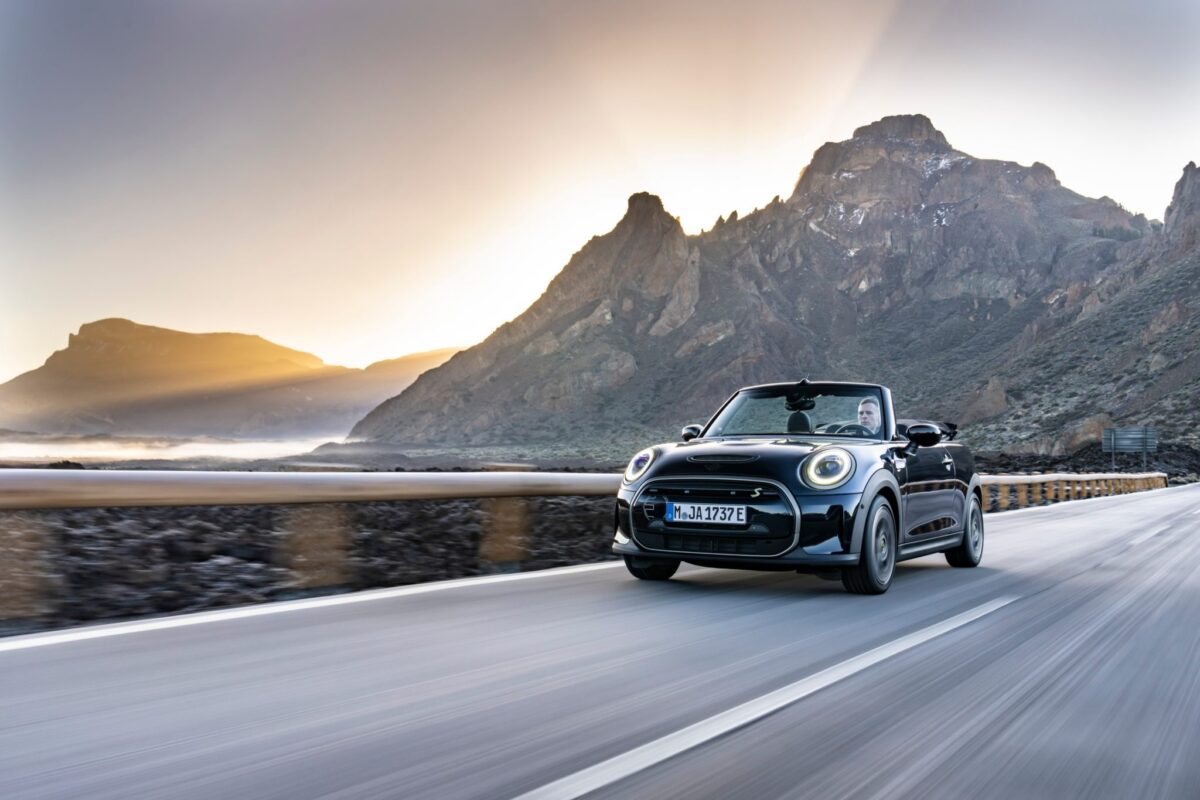Mini Cabriolet électrique nouvelle génération roulant sur une route de montagne au lever du soleil, symbole du plaisir de conduire et de la liberté signée Mini Equation.
