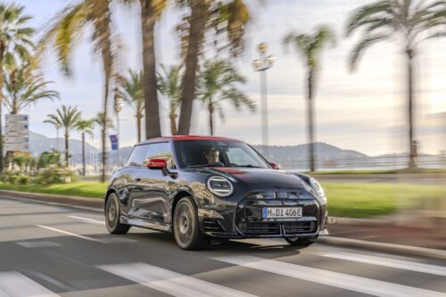 MINI Cooper SE noire et rouge roulant sur une route bordée de palmiers — illustration d’un article sur les formules LOA et LLD MINI à Toulouse.