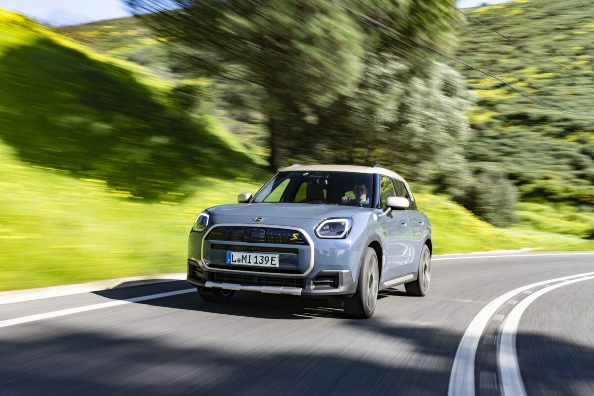 Mini Countryman hybride rechargeable en mouvement sur une route de campagne, SUV compact associant performance et écologie